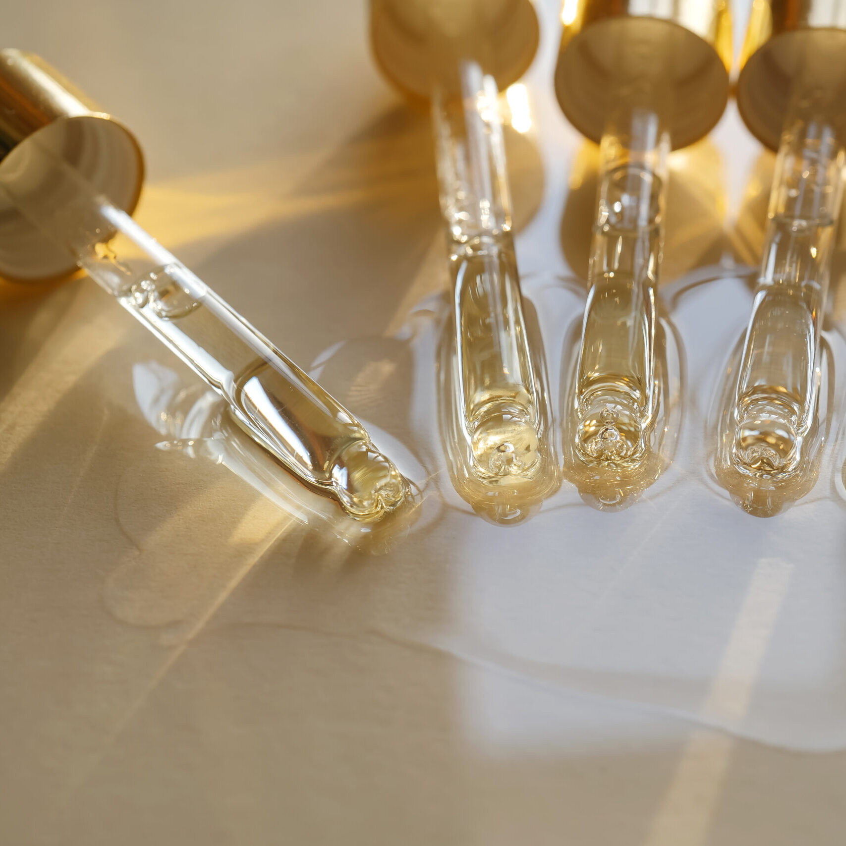 Pipettes with oil or serum on a golden background. Five pipettes with oil or serum on a golden background.